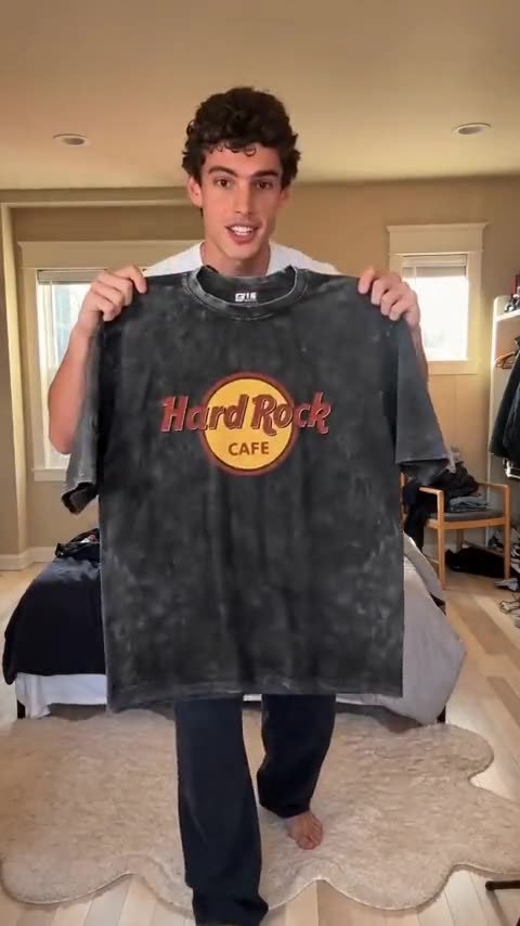 Frame from an AI UGC video: a young man showing his T-shirt to the camera
